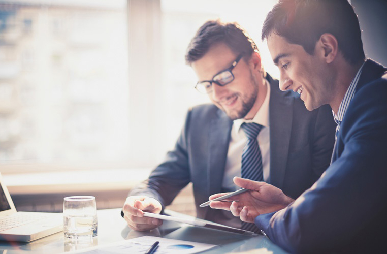 Homens sorrindo, olhando um tablet com um sistema de gestão para impulsionar o negócio deles