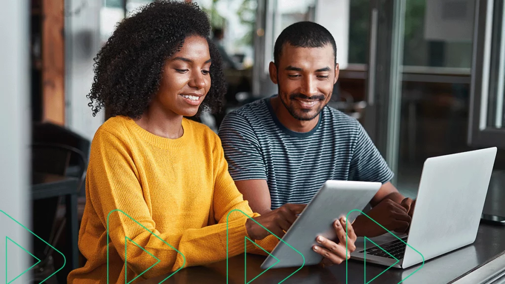 Empreendedores sorrindo enquanto usam seu sistema de gestão online no computador