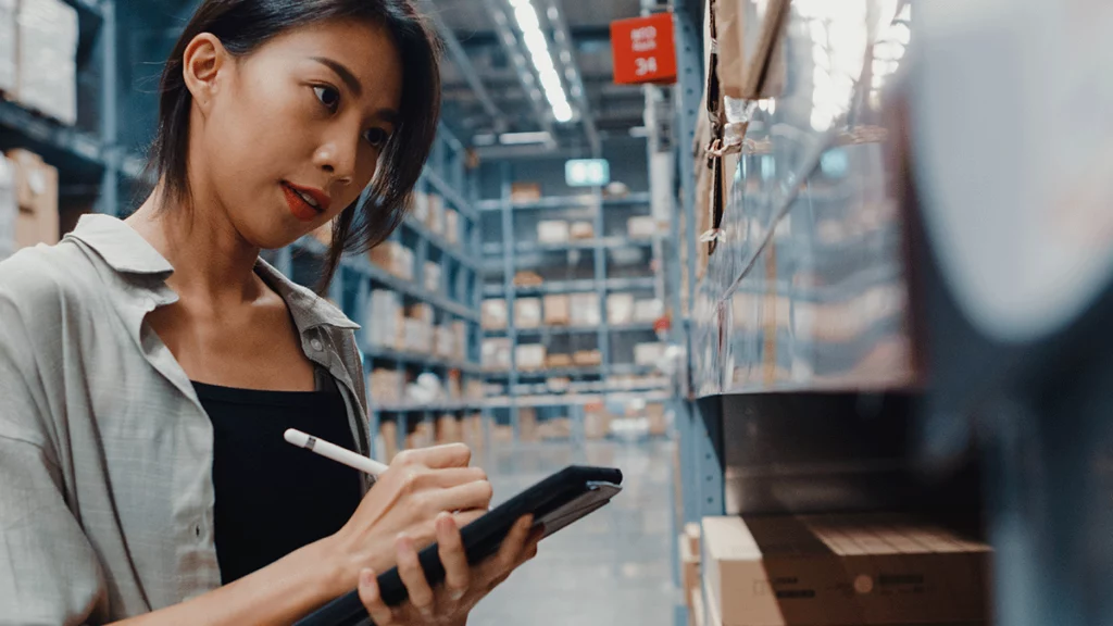 Mulher usando um sistema em um tablet para separar e organizar os produtos no depósito de uma loja de departamentos