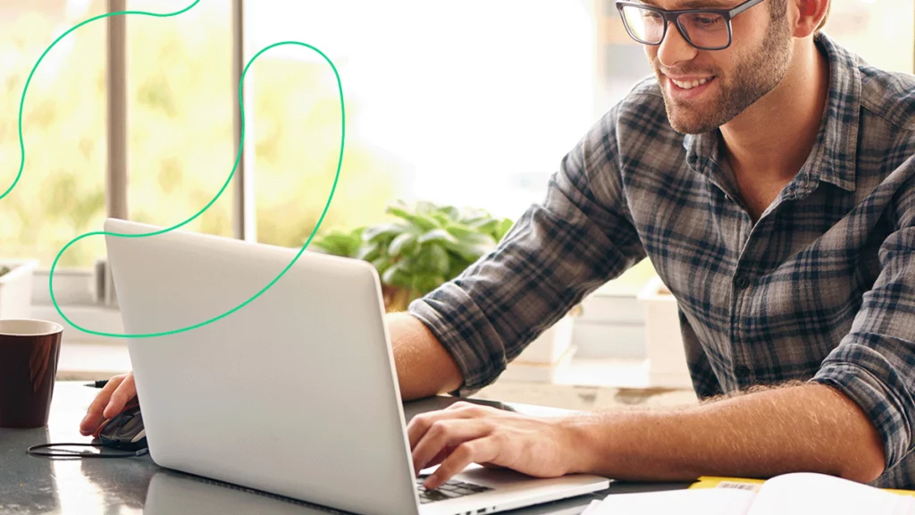 Homem sorrindo ao usar o seu computador, contente com a integração do Bling com a Irroba