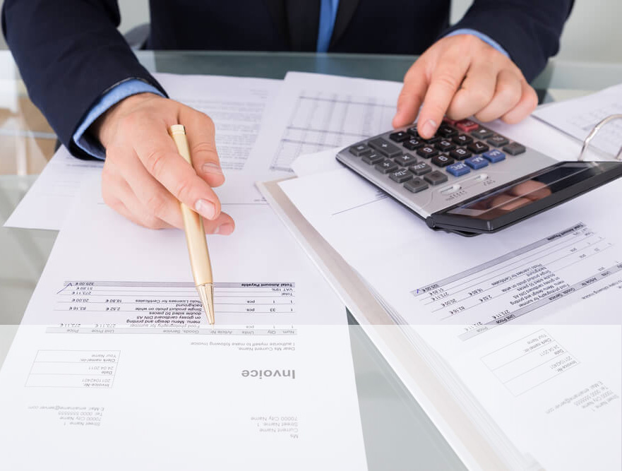 Empreendedor calculando os impostos de notas fiscais com papel, caneta e uma calculadora