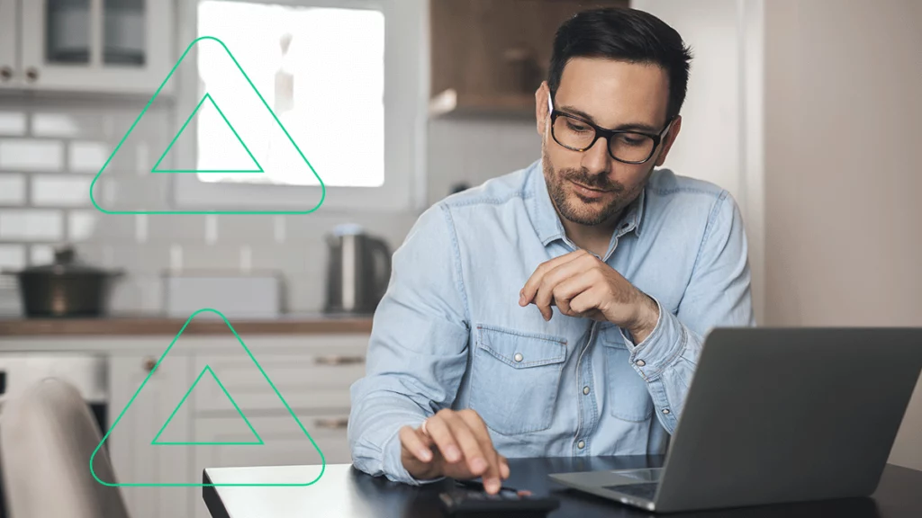 Homem com um laptop e uma calculadora, tentando entender como funciona o ICMS para e-commerce