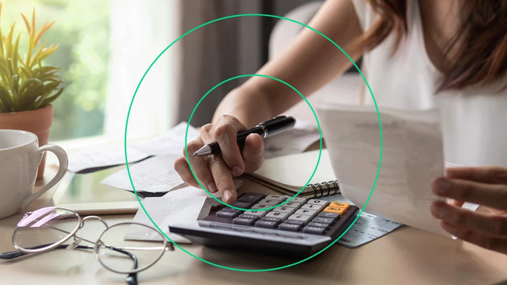 Empreendedora conferindo papéis e usando uma calculadora para descobrir os valores do PIS e COFINS