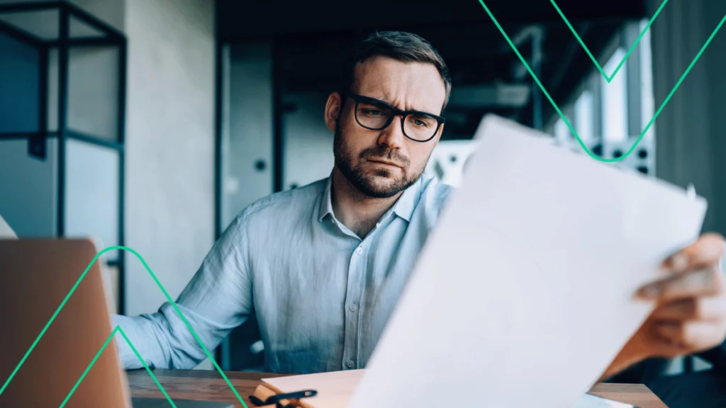 Homem com expressão preocupada e triste olhando para um boleto vencido em sua mão