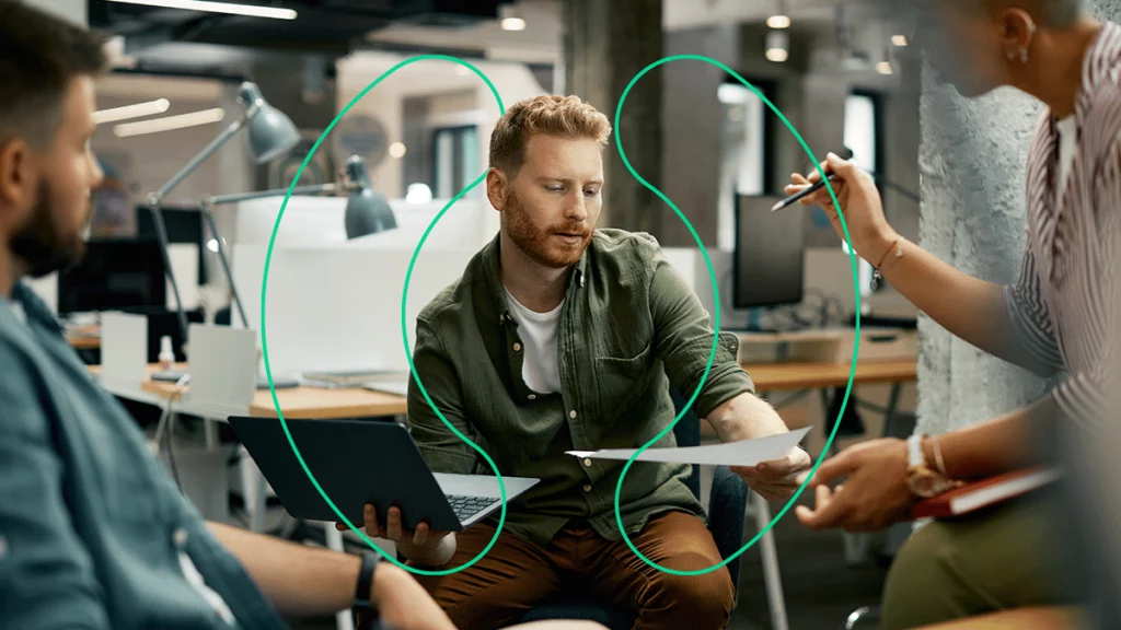 3 pessoas em uma empresa, analisando documentos e discutindo sobre como reduzir custos de software