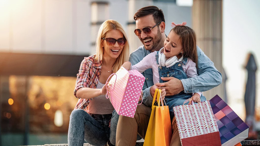 Família cheia de sacolas de presentes rindo, alegres com os presentes para o Dia das Mães