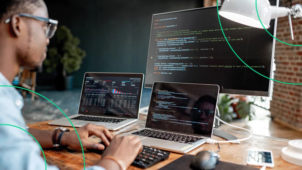 Homem com 3 telas de computadores na sua frente, escrevendo código para blindar o site