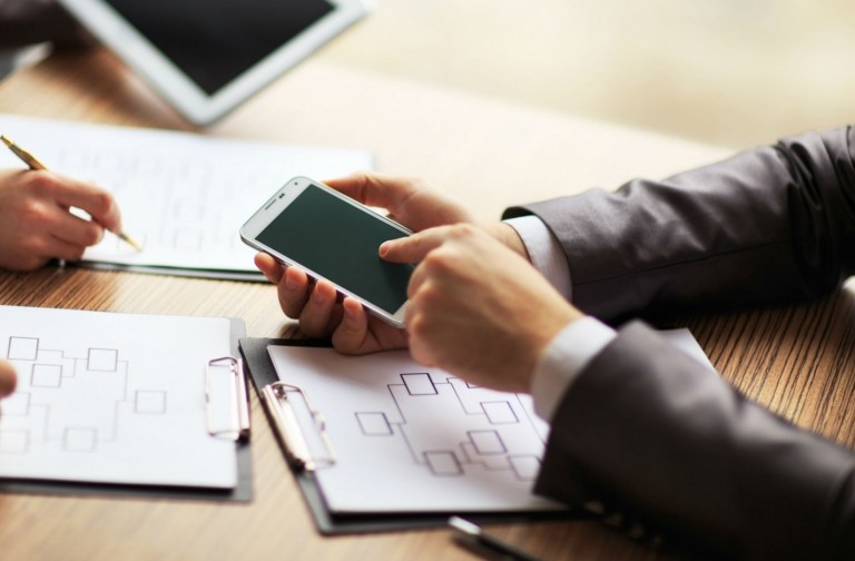 Empreendedor explicando para outras pessoas como funciona o WhatsApp Business, apontando para o mesmo na tela do seu celular