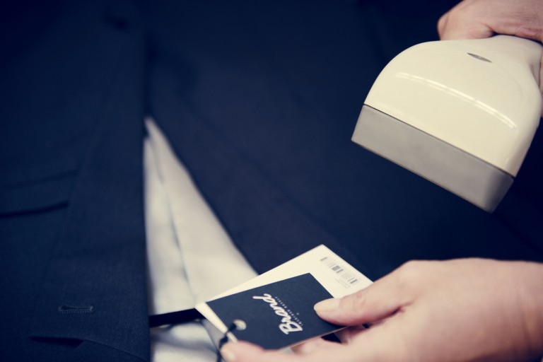 Pessoa escaneando o GTIN em uma etiqueta presa em uma roupa