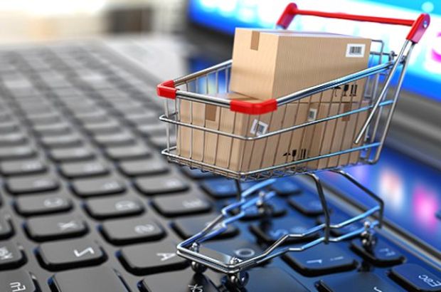 Miniatura de um carrinho de supermercado com caixas de e-commerce em cima de um notebook aberto