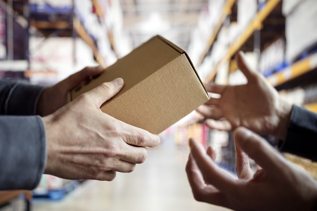 Uma pessoa entrega uma caixa para outra pessoa, representando a integração das logísticas
