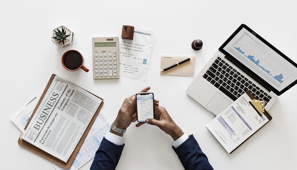 Em uma mesa com vários papéis, computador, anotações e relatórios, empreendedor analisa opções de empréstimos online