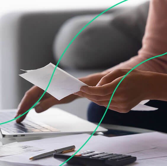 Empreendedora analisando nota fiscal em sua mão e no computador