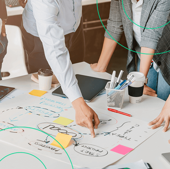 Grupo de empreendedores olhando e discutindo sobre um plano de ação desenhado num grande papel