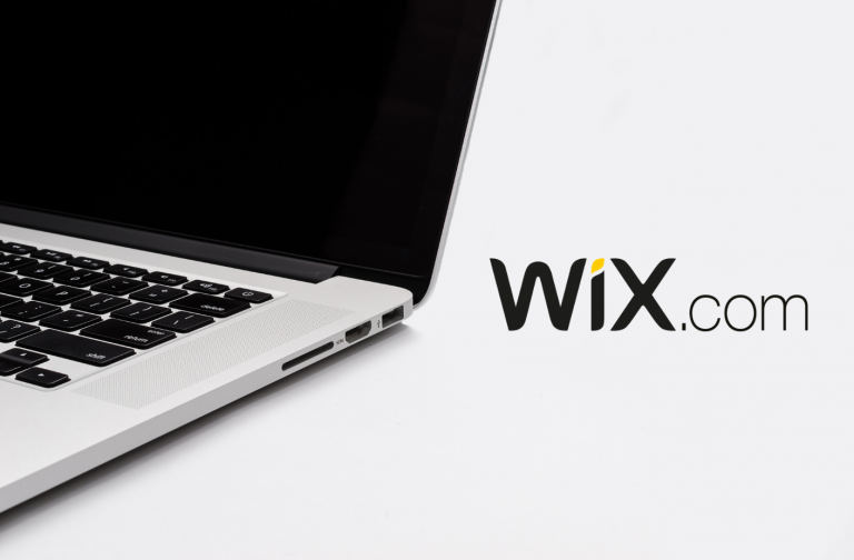 Foto de uma parte de um laptop, com o logotipo Wix.com em destaque ao lado