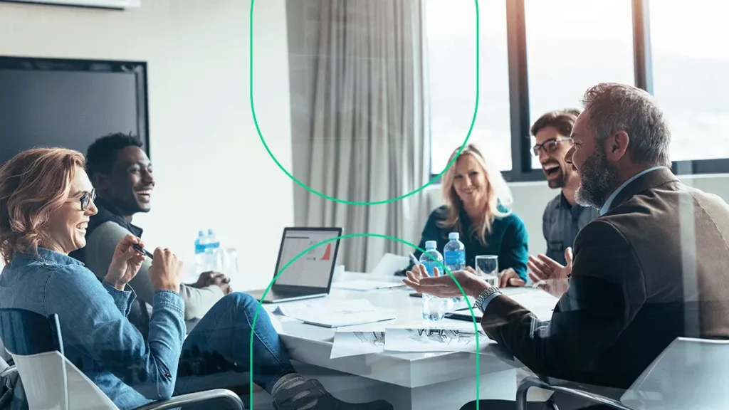 Várias pessoas conversando e sorrindo numa sala de reuniões de uma empresa
