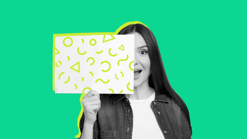 Mulher sorrindo para a câmera, segurando uma folha de papel colorido na mão