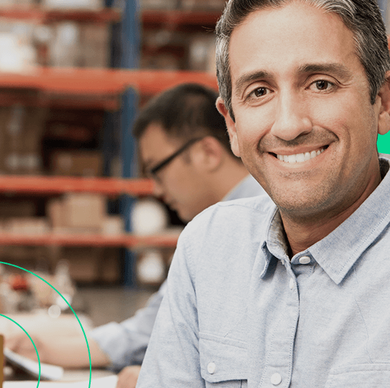 Empreendedor no depósito da empresa, sorrindo para a câmera em meio ao seu estoque