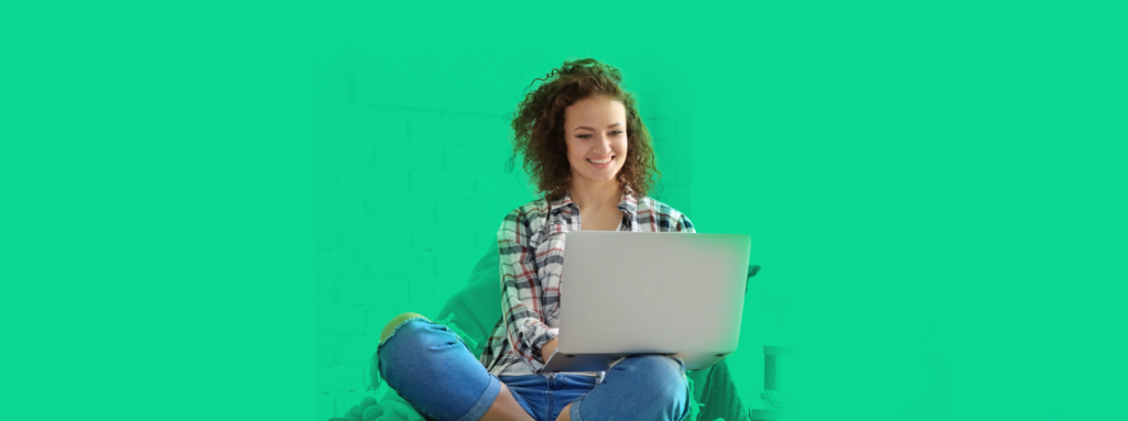 Mulher sentada com um laptop no colo, sorrindo ao entender como funciona o MEI