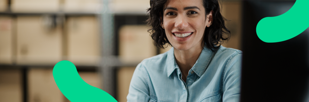 Mulher em seu armazém, sorrindo para a câmera, feliz com sua conta digital com sistema de gestão