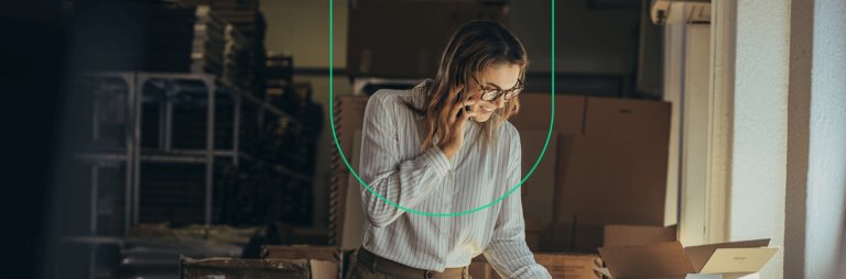 Mulher de negócios falando no celular enquanto confere documentos em seu local de trabalho, planejando seu e-commerce B2B