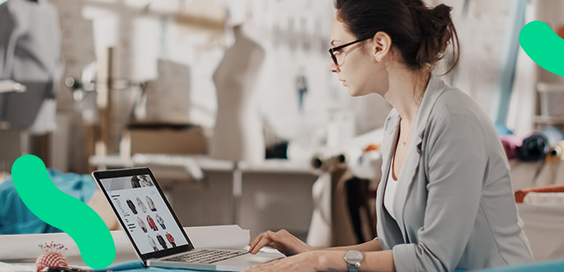 Em seu estúdio, empreendedora da moda verifica seu e-commerce no computador
