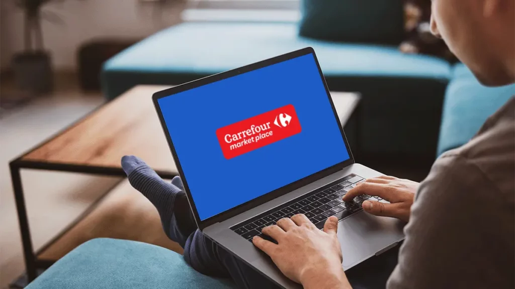 Homem sentado com notebook no colo, olhando para o Carrefour Marketplace na tela